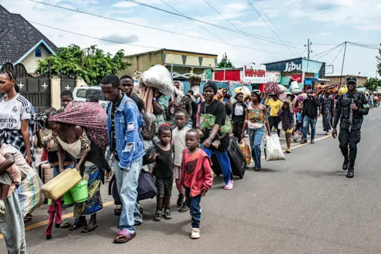 أحد أفراد قوات الأمن الرواندية يرافق مجموعة من النازحين من الكونغو لدى وصولهم إلى رواندا
